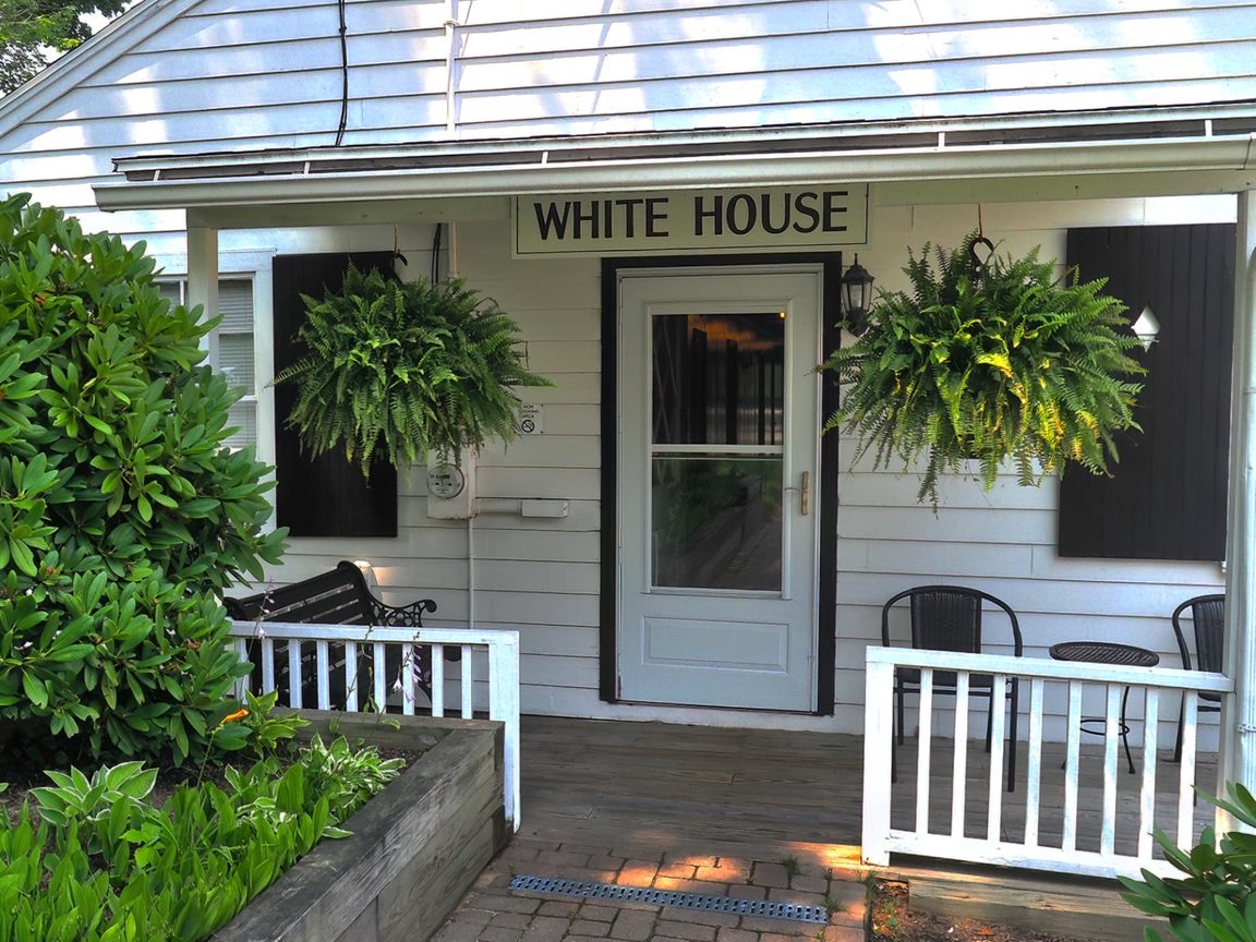 A white building with a bench and table placed outside.