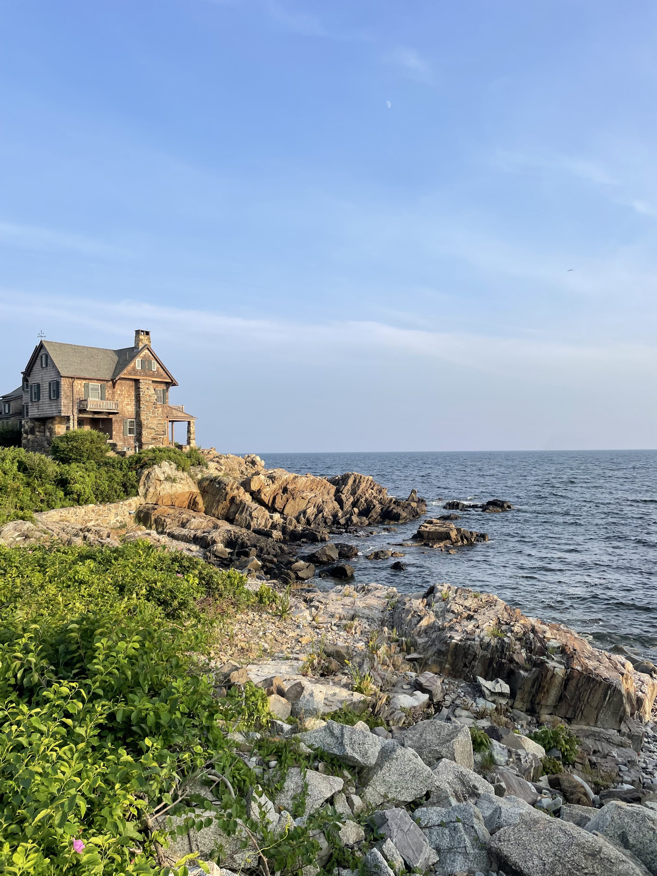 A small brown brick house on a rocky promontory overlooking the sea.